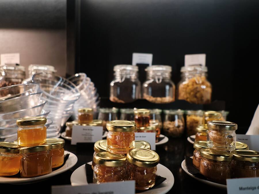 A display of various jars of honey on plates with labels, likely in a store or cafe setting.
