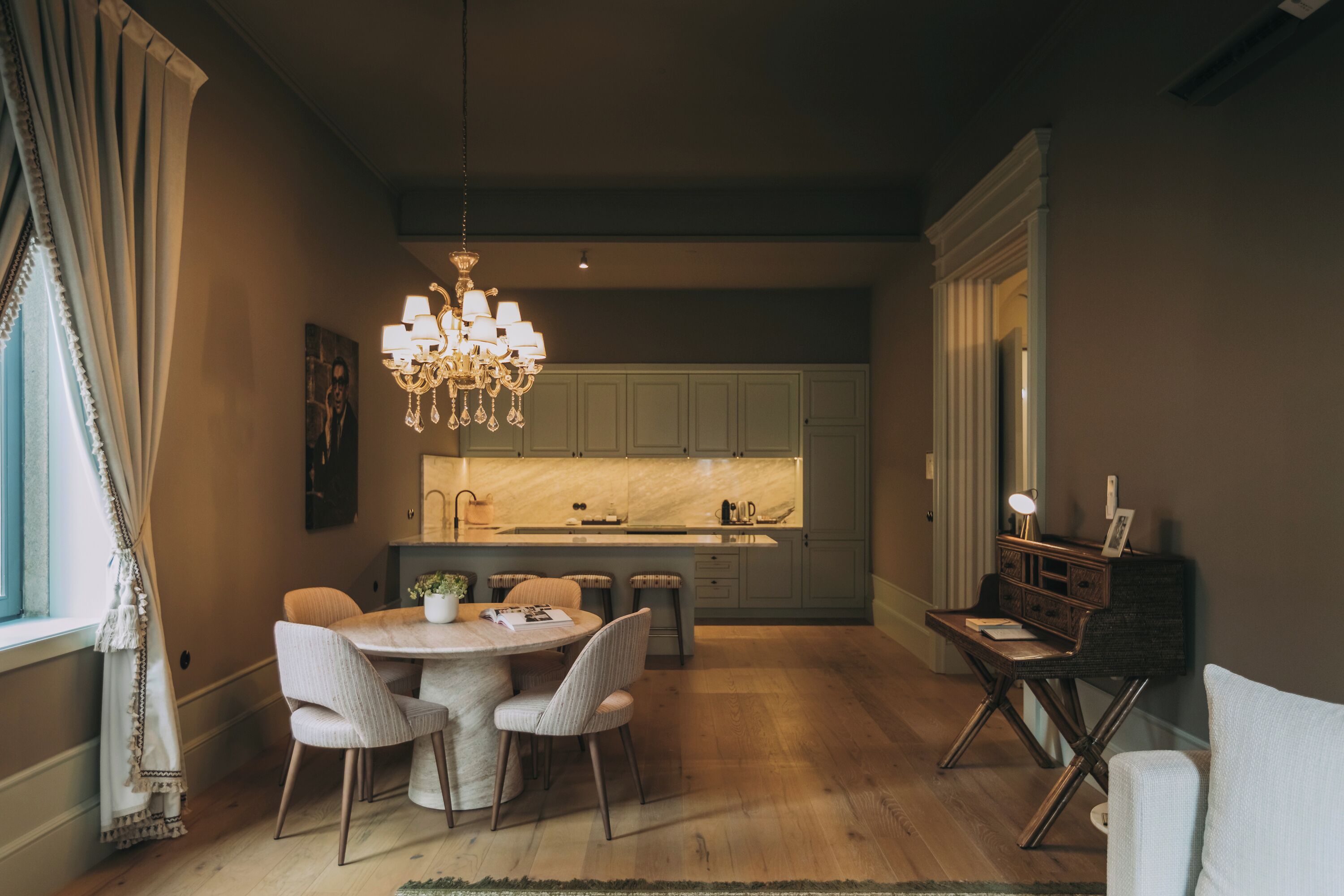 Cocina moderna con una isla central, iluminación colgante y un comedor con sillas y una mesa.