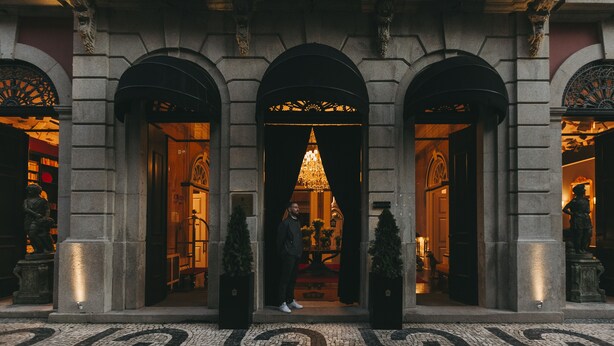 A grand entrance with a central archway, flanked by two columns, leading to a warmly lit interior. - Torel Palace Porto (Porto)