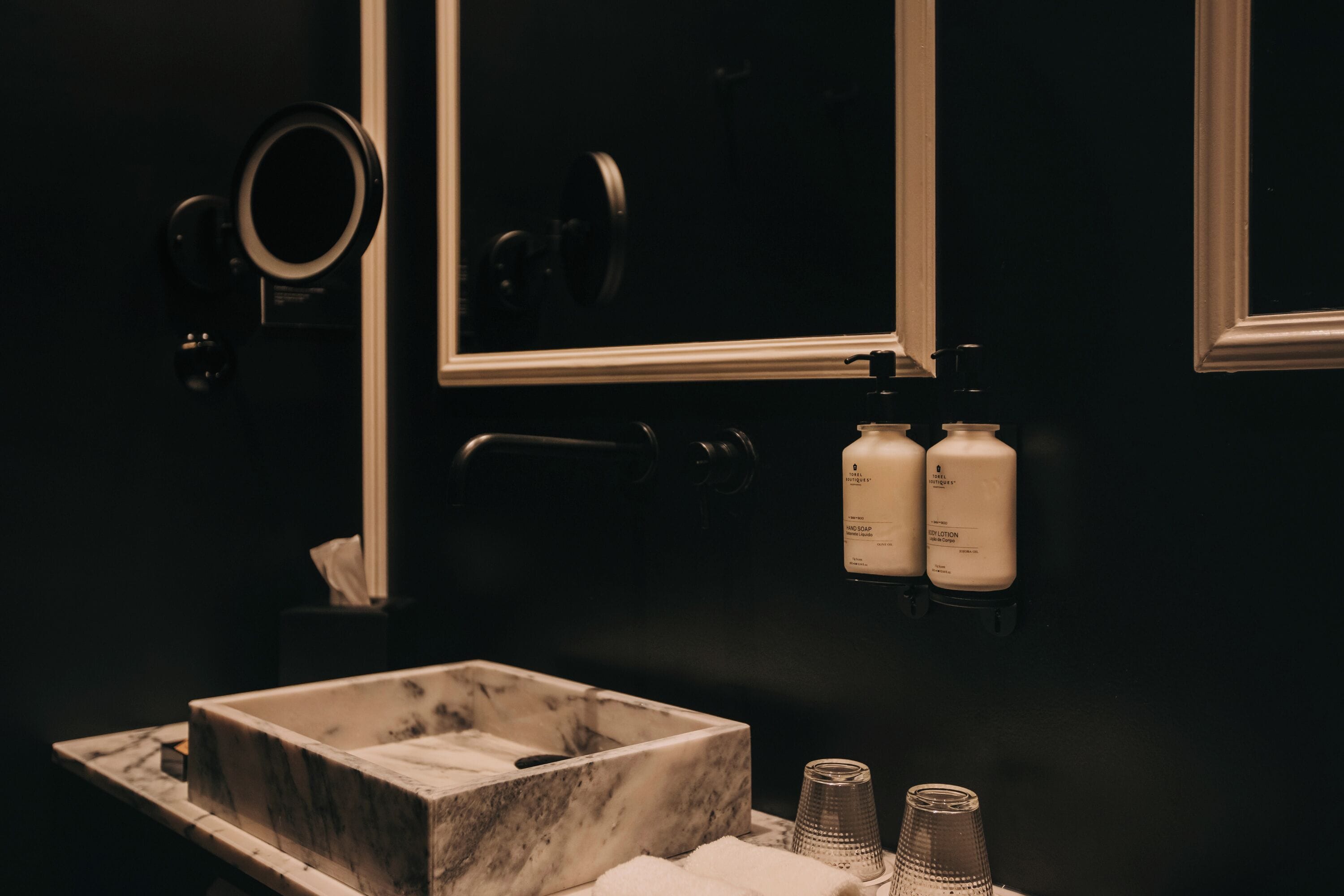 A bathroom with a marble sink, two toiletry bottles, a mirror, and a towel.