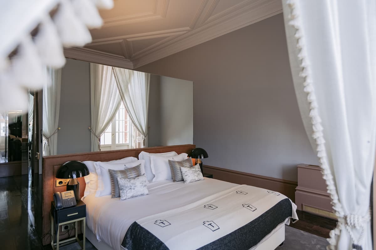 Une chambre d’hôtel bien aménagée, avec un grand lit, des lampes de chevet, un téléphone sur la table de chevet et un miroir.
