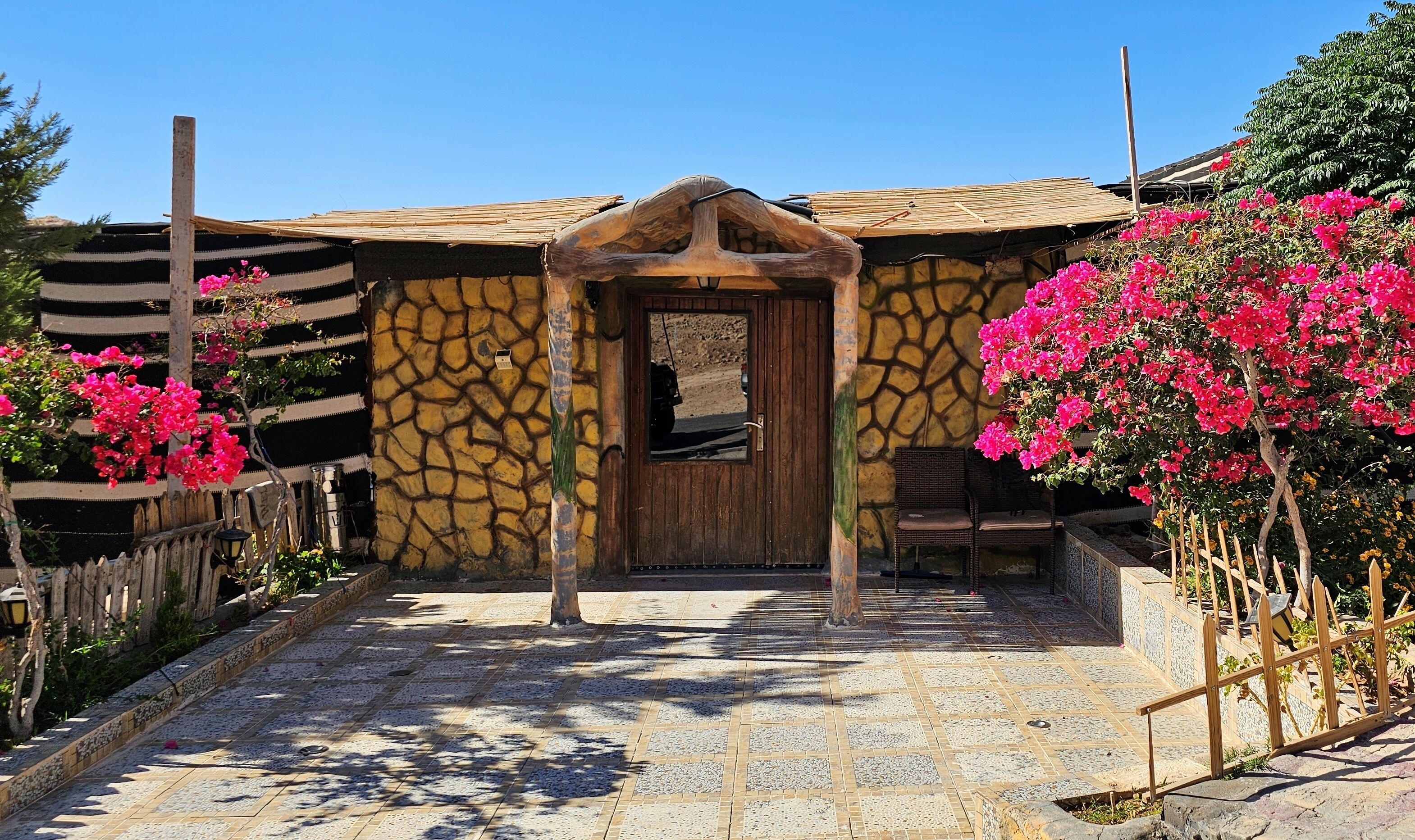 A stone-walled building with a wooden door and a tiled entrance.