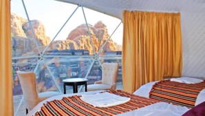 A room with a bed, a chair, a table, and a window with curtains. - Seven Wonders Luxury Camp (Wadi Musa)