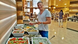 A buffet area with various food dishes and a person serving food. - Seven Wonders Luxury Camp (Wadi Musa)