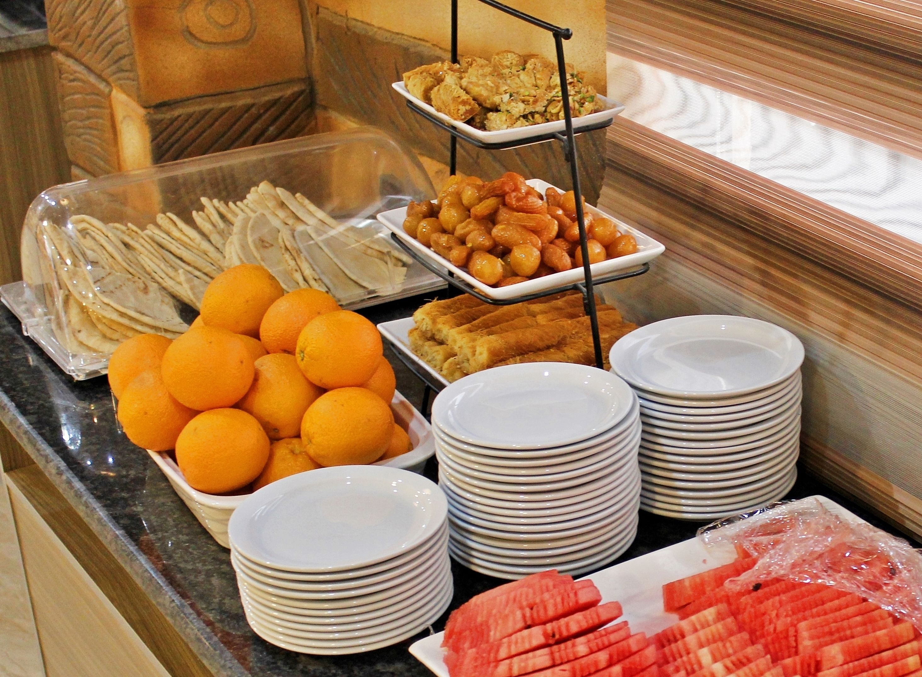 A buffet with various food items including oranges, bread, and other dishes.