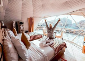Ein gemütliches Zimmer mit einem großen Bett, einem kleinen Tisch und Blick auf eine Brücke.