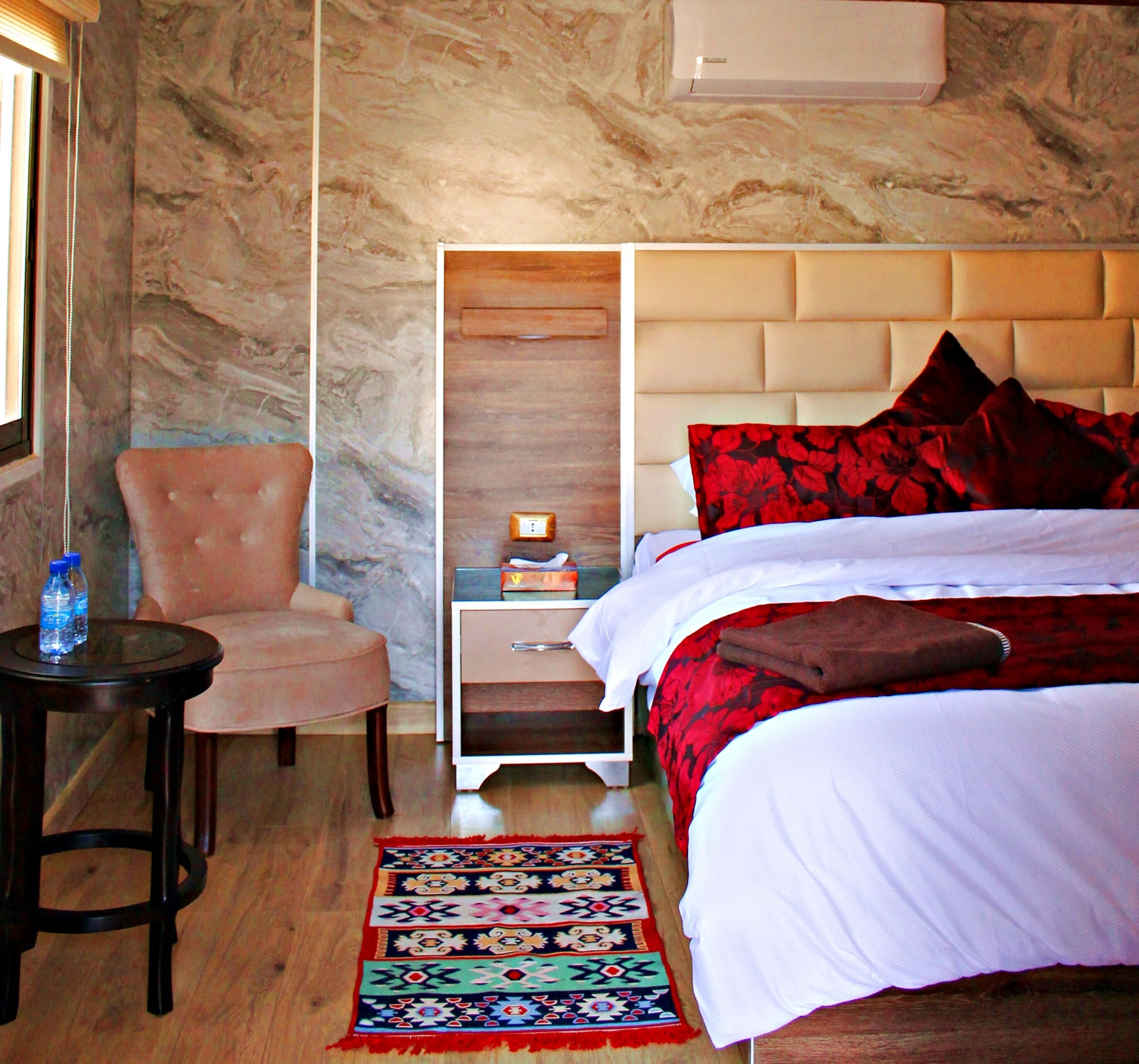 A hotel room with a bed, a chair, a nightstand, and a rug.