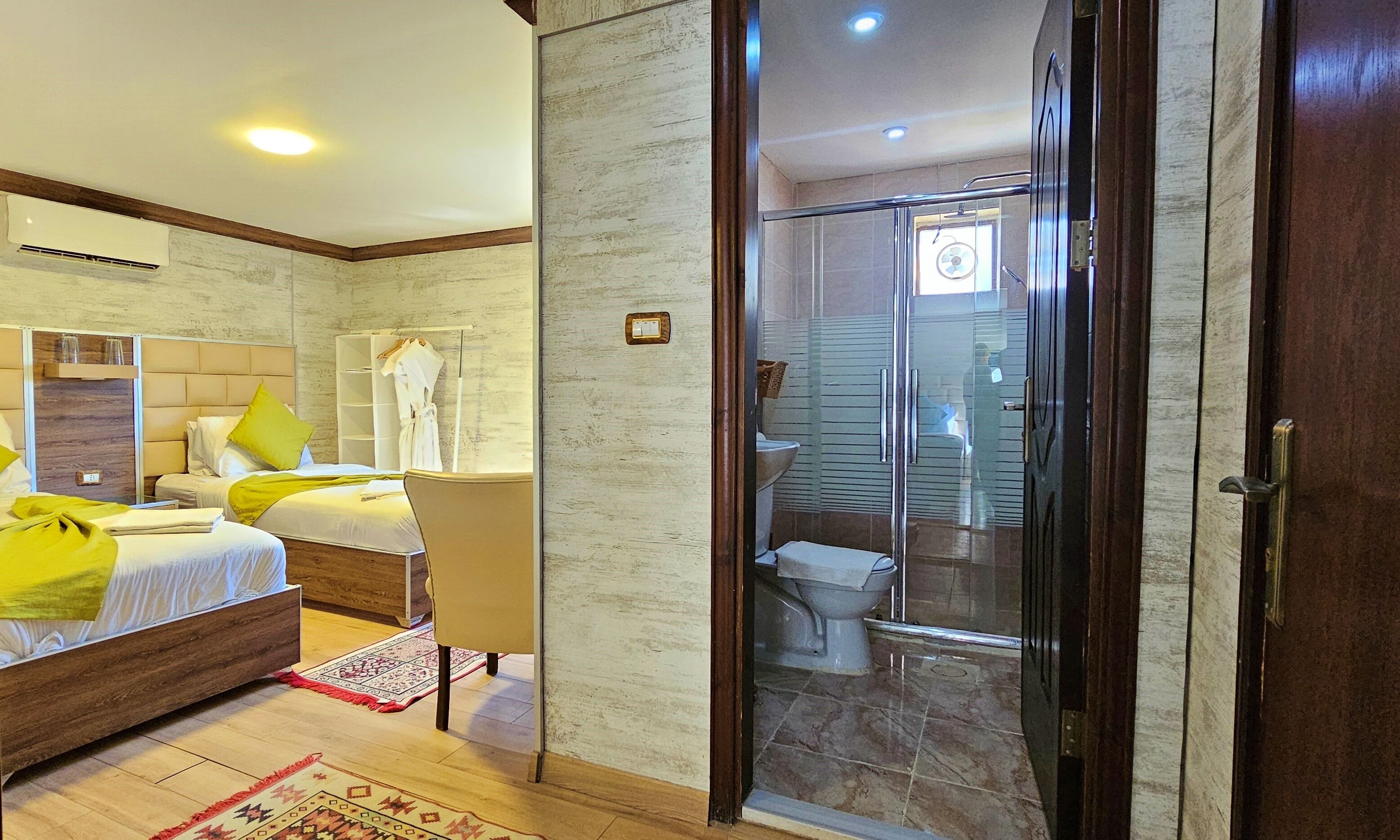 A hotel room with a bed, bedside table, and a bathroom with a shower and toilet.