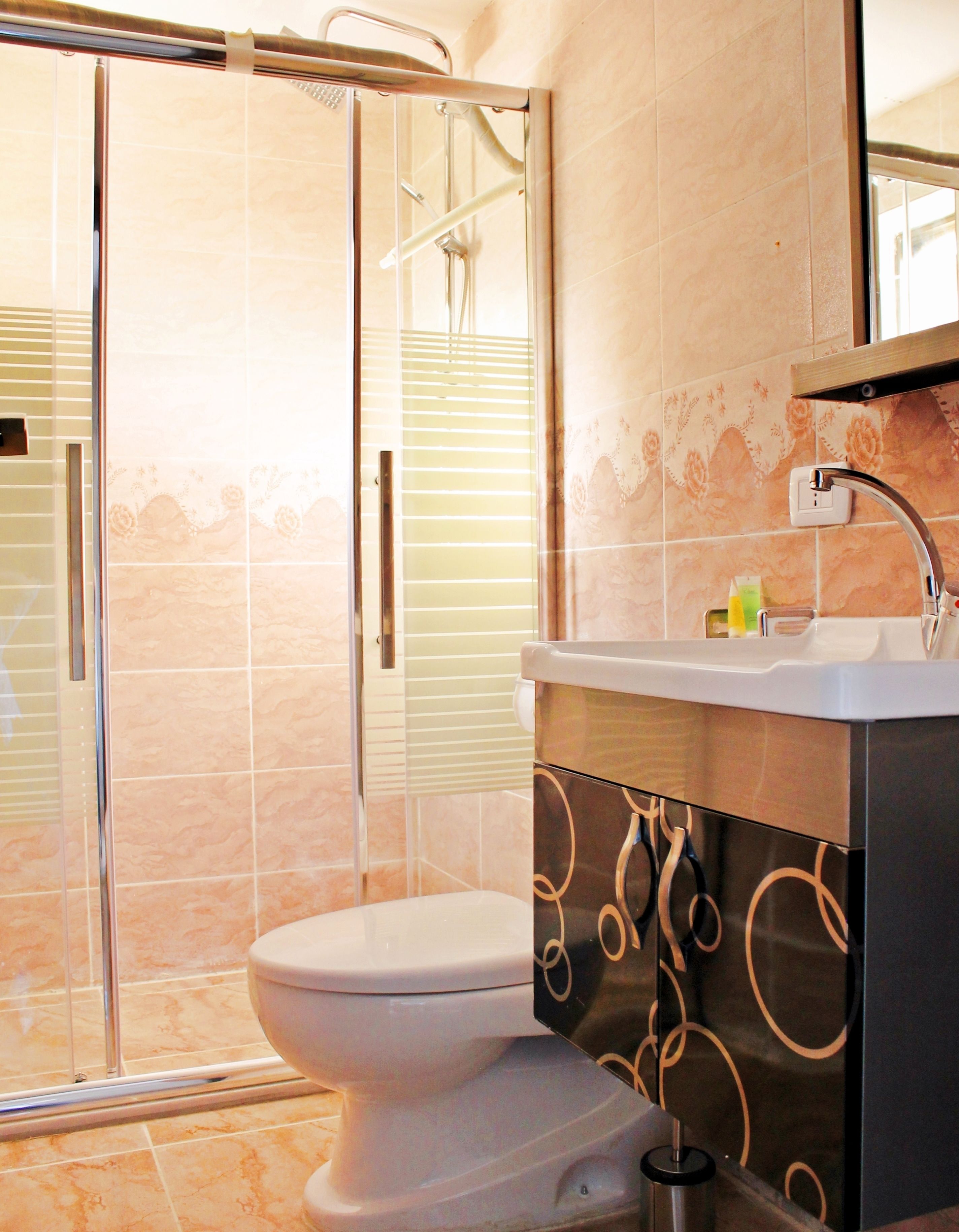Une salle de bain avec une douche à parois de verre, des toilettes blanches et un meuble-lavabo avec un miroir et un évier.