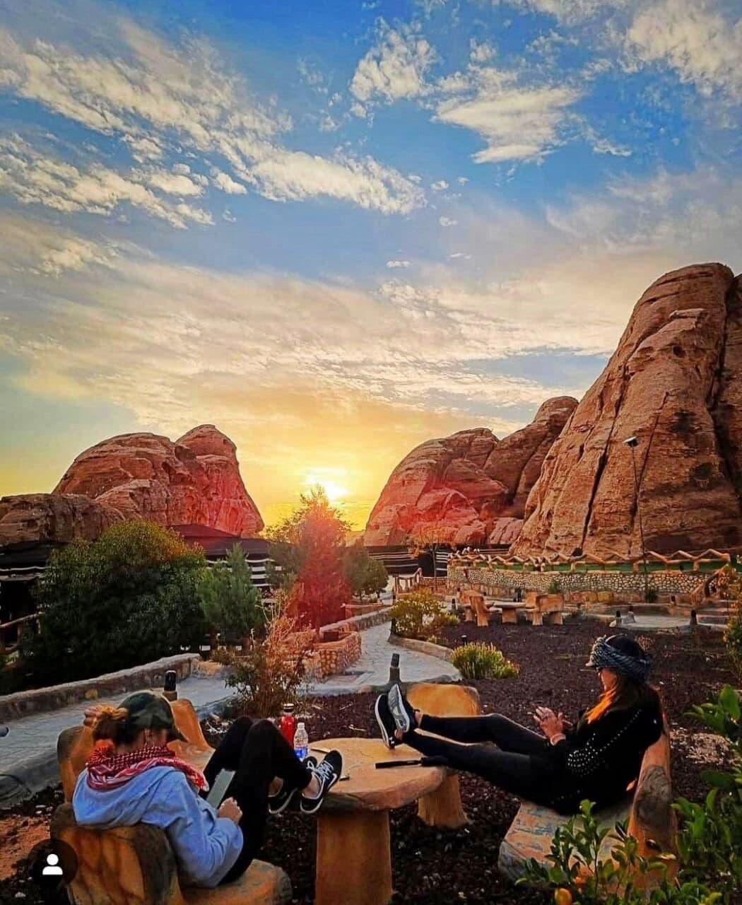 A sunset view with two people relaxing on outdoor seating.