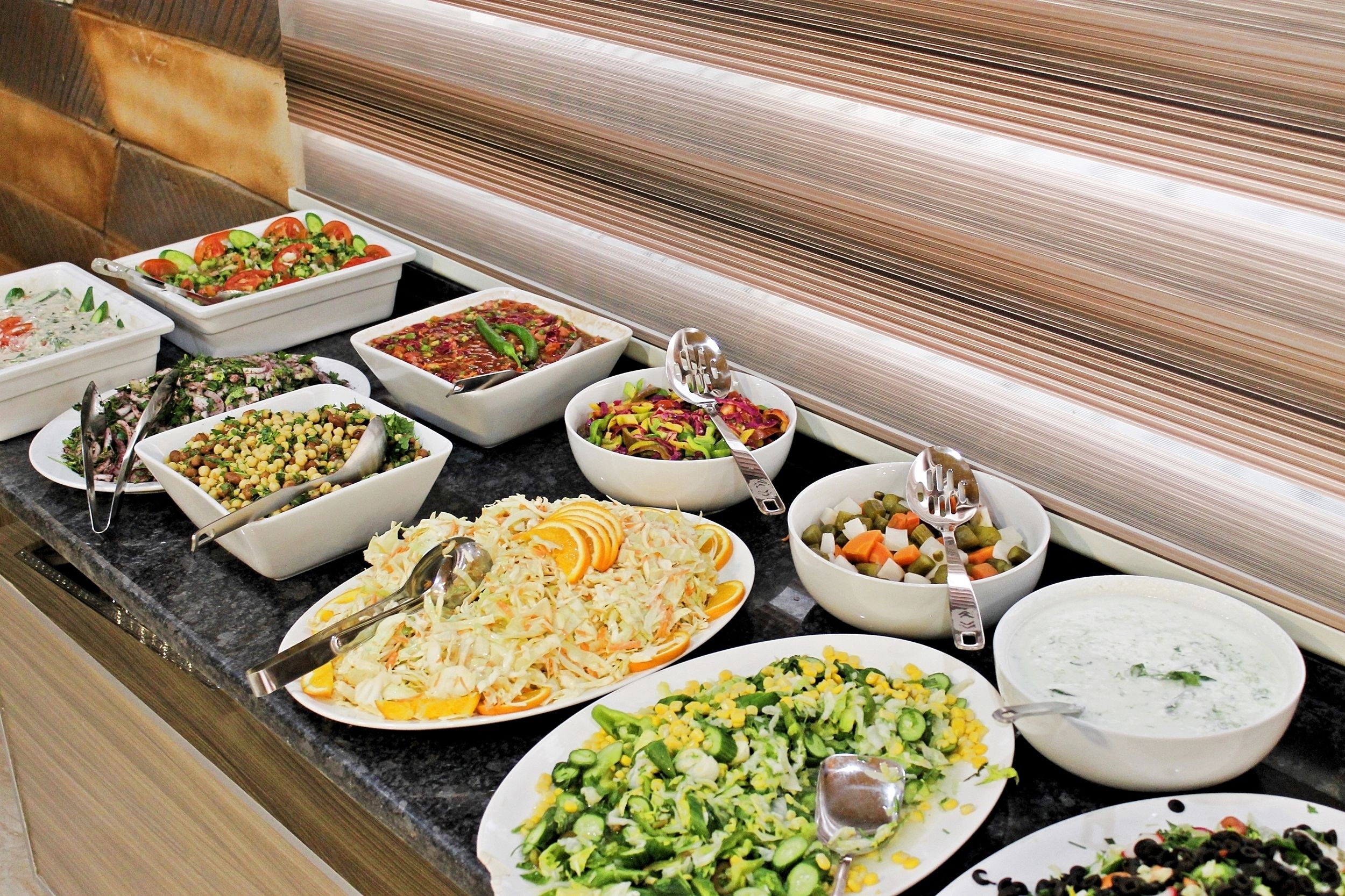 A buffet with various dishes including salads, coleslaw, and a bowl of soup.