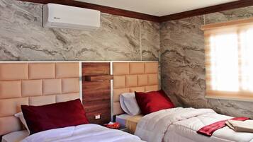 Habitación de hotel con dos camas, paredes de mármol, cabecero de madera y un equipo de aire acondicionado.