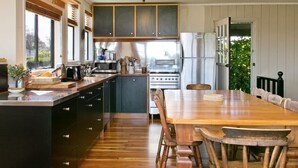 A kitchen with wooden cabinets, a central island, a dining table with chairs, and a refrigerator.