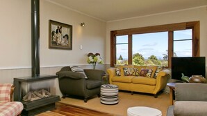 A cozy living room with a fireplace, a sofa, a yellow armchair, and a television.