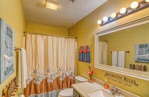 A bathroom with a large mirror, a shower curtain, and a sink with a decorative bird statue.