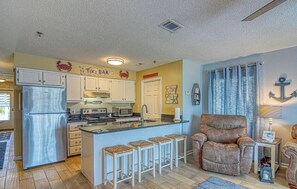 A compact kitchen with a central island, white cabinets, and a bar sign. - Oceanview Paradise: Relaxing 2-Bedroom Condo in Surfside Beach (Surfside Beach)
