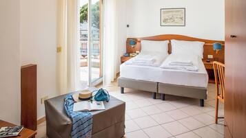 Ein Hotelzimmer mit Bett, Schreibtisch, Stuhl, einem Fenster mit Ausblick und einer Wandlampe.