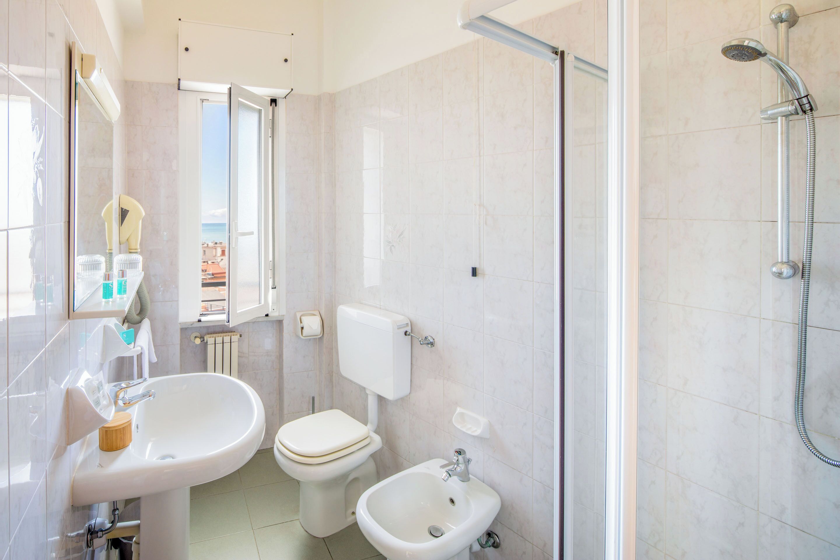 A bathroom with a sink, toilet, bidet, and shower.
