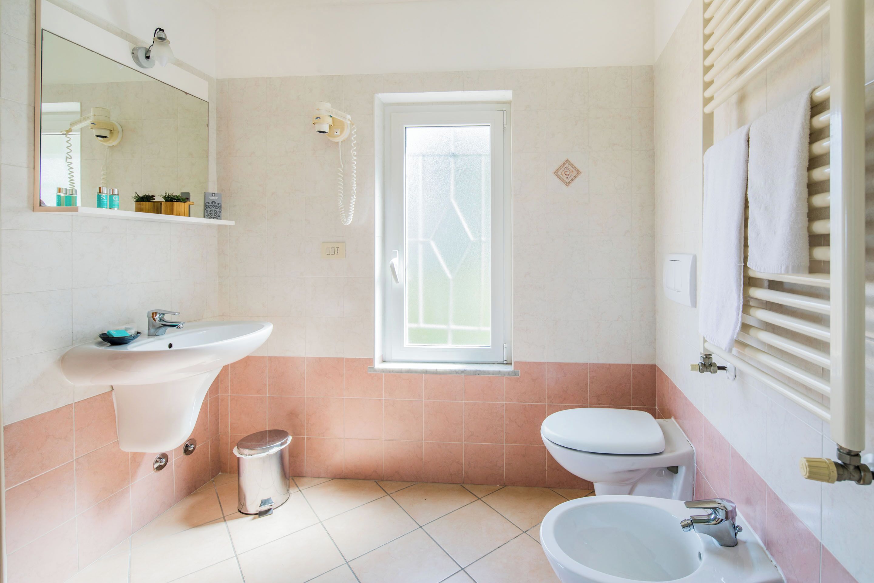 Une salle de bain équipée d’un lavabo, de toilettes, d’un bidet et d’une fenêtre.