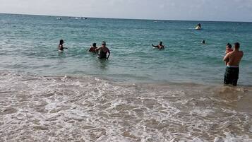 Di pantai, pasir putih, payung pantai, dan handuk pantai