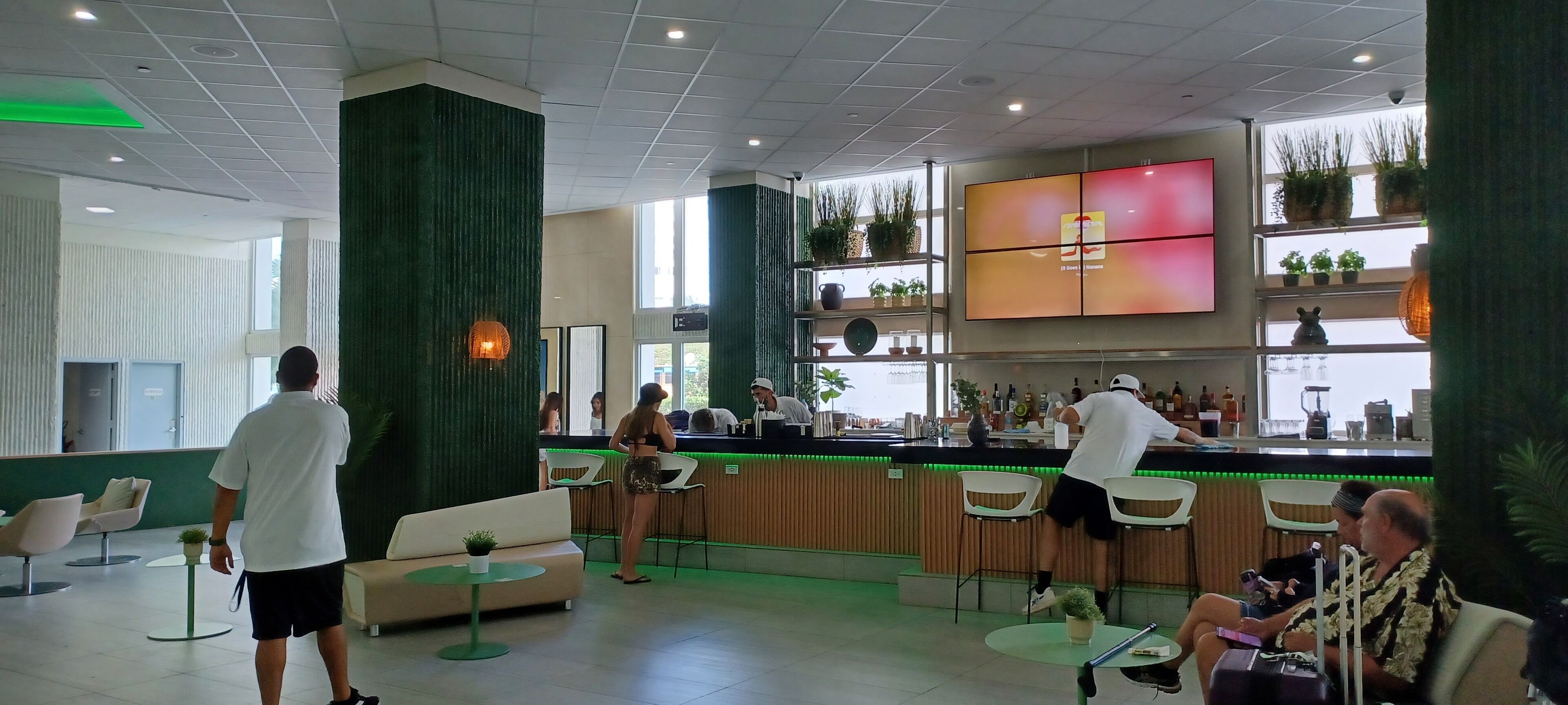 A modern bar area with a counter, seating, and a TV screen.