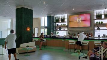 A modern bar area with a counter, seating, and a TV screen.