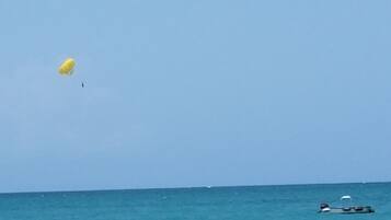 A clear blue sky over a calm sea with a yellow parasail and a small boat in the distance.