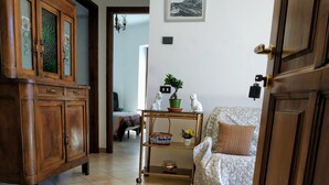 A room with a wooden cabinet, a bed with a quilt, a small table with a plant, and a wall-mounted picture. - Casa Marina .. a stone's throw from the center! (Verbania)