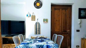 A dining area with a table set for four, a television, and a wooden door. - Casa Marina .. a stone's throw from the center! (Verbania)