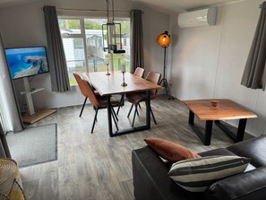 Un salon moderne avec une table à manger en bois, un canapé en cuir et un téléviseur posé sur un meuble.