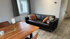 A modern living room with a wooden dining table, leather sofa, and a radiator. - RBR 264 - Beach Resort Kamperland (Kamperland)