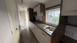 A compact kitchen with a built-in sink, a window above the sink, and a door leading to another room. - RBR 264 - Beach Resort Kamperland (Kamperland)