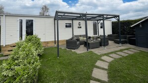 A caravan with a covered patio area, outdoor furniture, and a small garden. - RBR 264 - Beach Resort Kamperland (Kamperland)