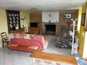 A living room with a sofa, a wooden coffee table, a fireplace, and a television.