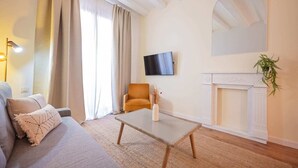 Una sala de estar con un sofá, una mesa de centro, un televisor montado en la pared y una chimenea.
