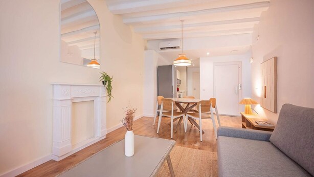 Una sala de estar con chimenea, un comedor con mesa y sillas, un sofá y una lámpara.