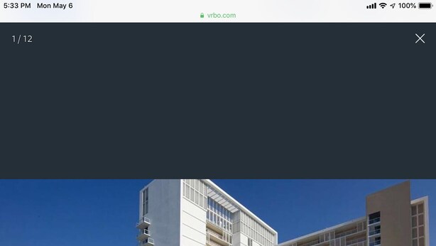 Ein modernes Hotel mit mehreren Etagen, einem Poolbereich inklusive Liegestühlen und Palmen.