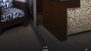 Eine Lobby mit einer Rezeption, einer blauen Wand, einem Fernseher, der eine Strandansicht zeigt, und einer dekorativen Schwane Skulptur.