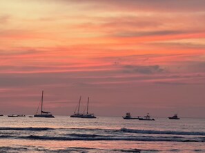 Een zonsondergang boven de oceaan met enkele boten.