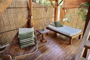 A wooden deck with a hanging chair and a bench, both with cushions. - The Beach Bungalows Tamarindo B&B (Tamarindo)