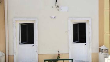 A building facade with two white doors, a small window, and a sign above the doors.