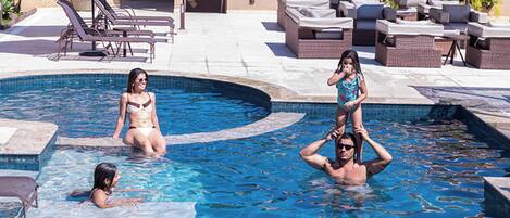 A swimming pool area with lounge chairs and a pergola.