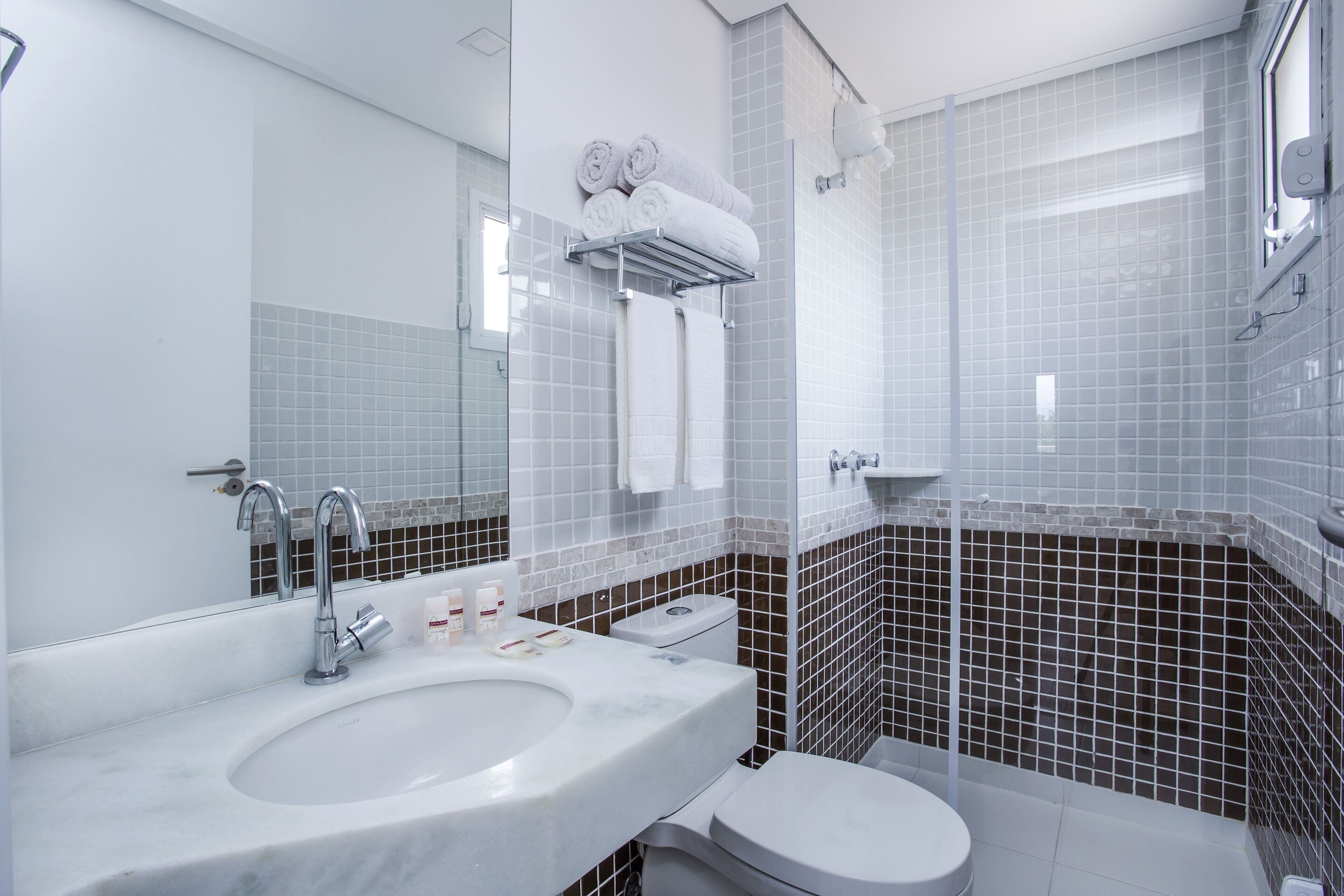 Un bagno moderno con un lavandino bianco, un water e un box doccia in vetro.