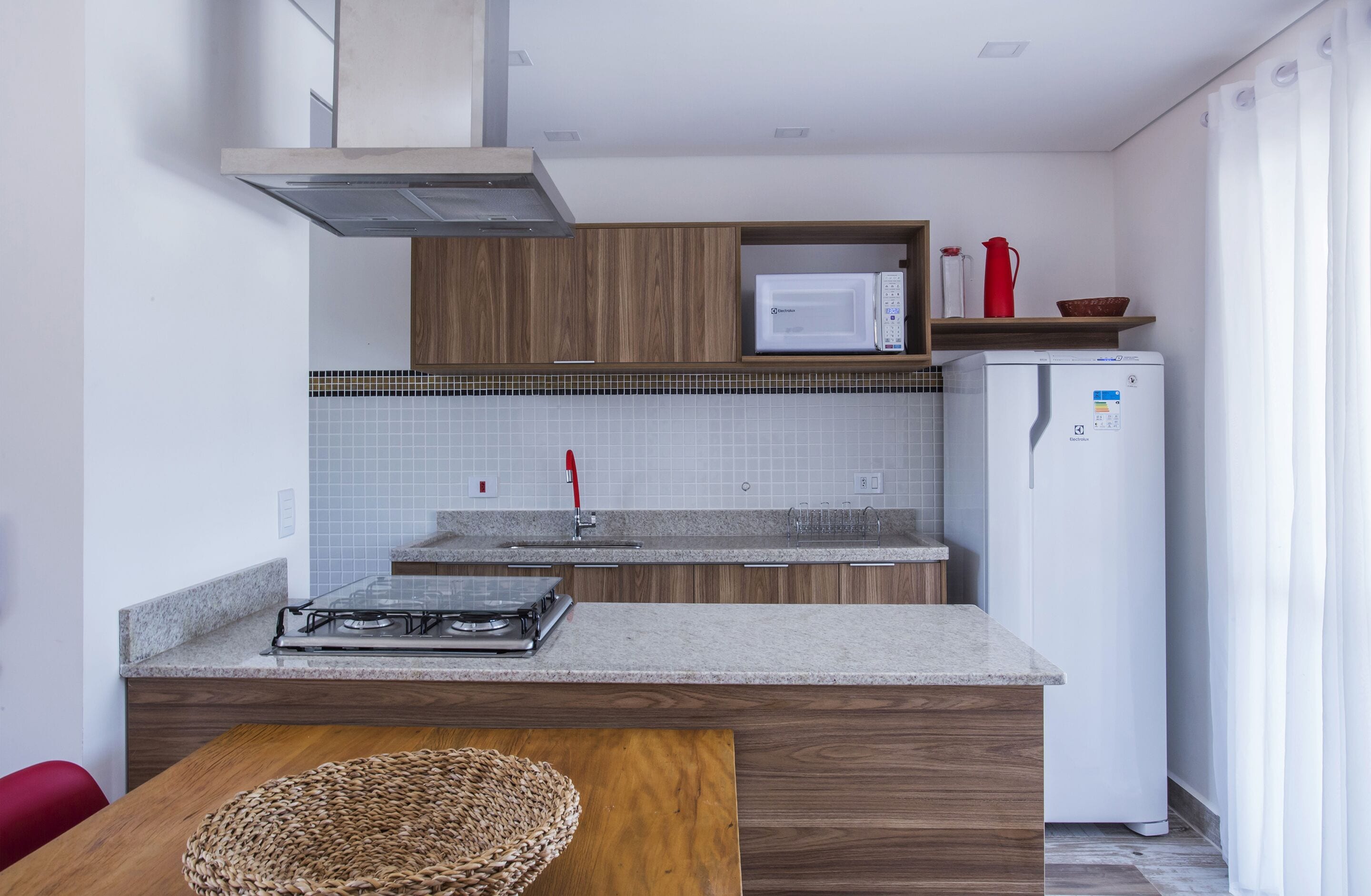 A compact kitchen with a microwave, refrigerator, and gas stove.