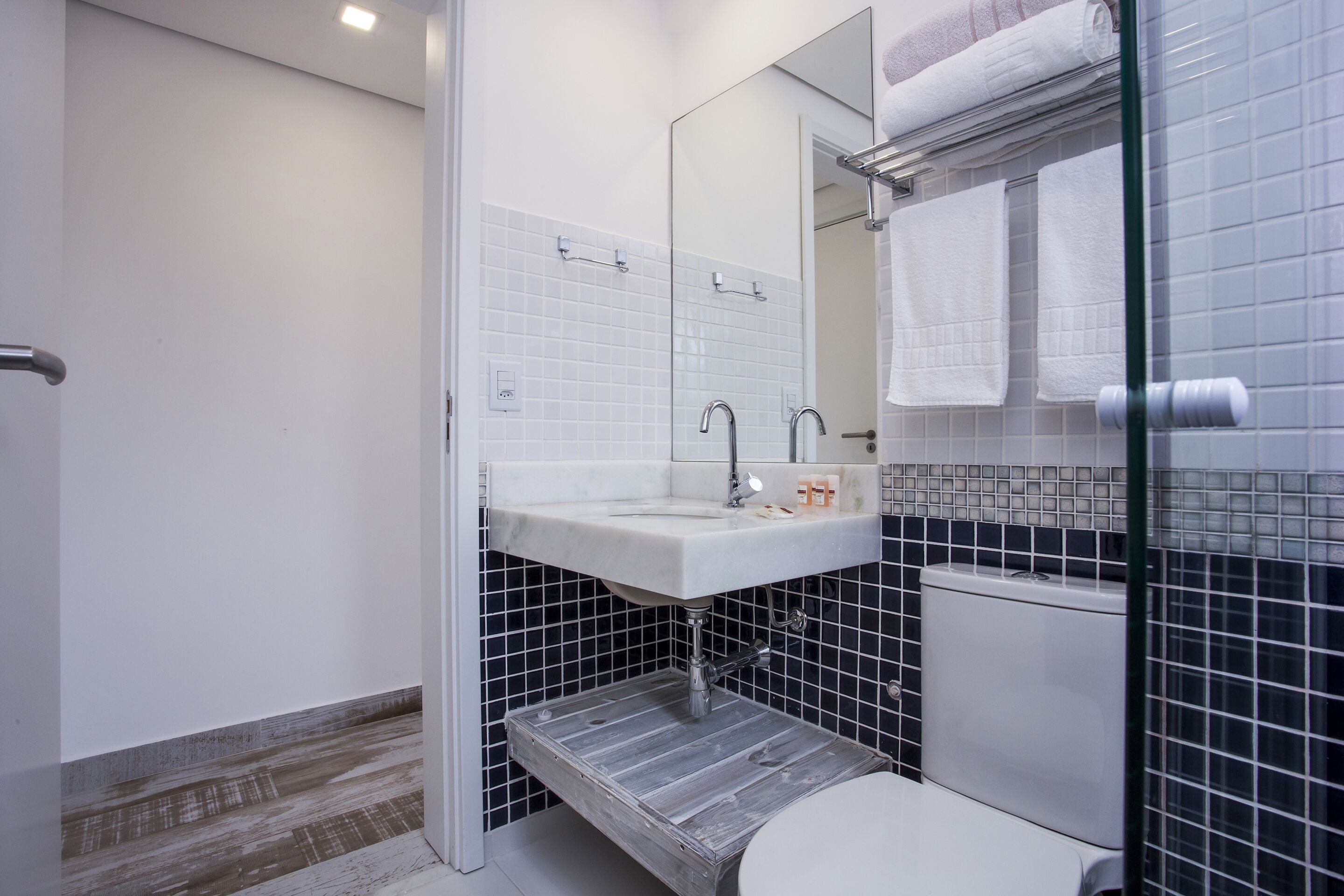 A bathroom with a white sink, a mirror, a toilet, and a shower area.