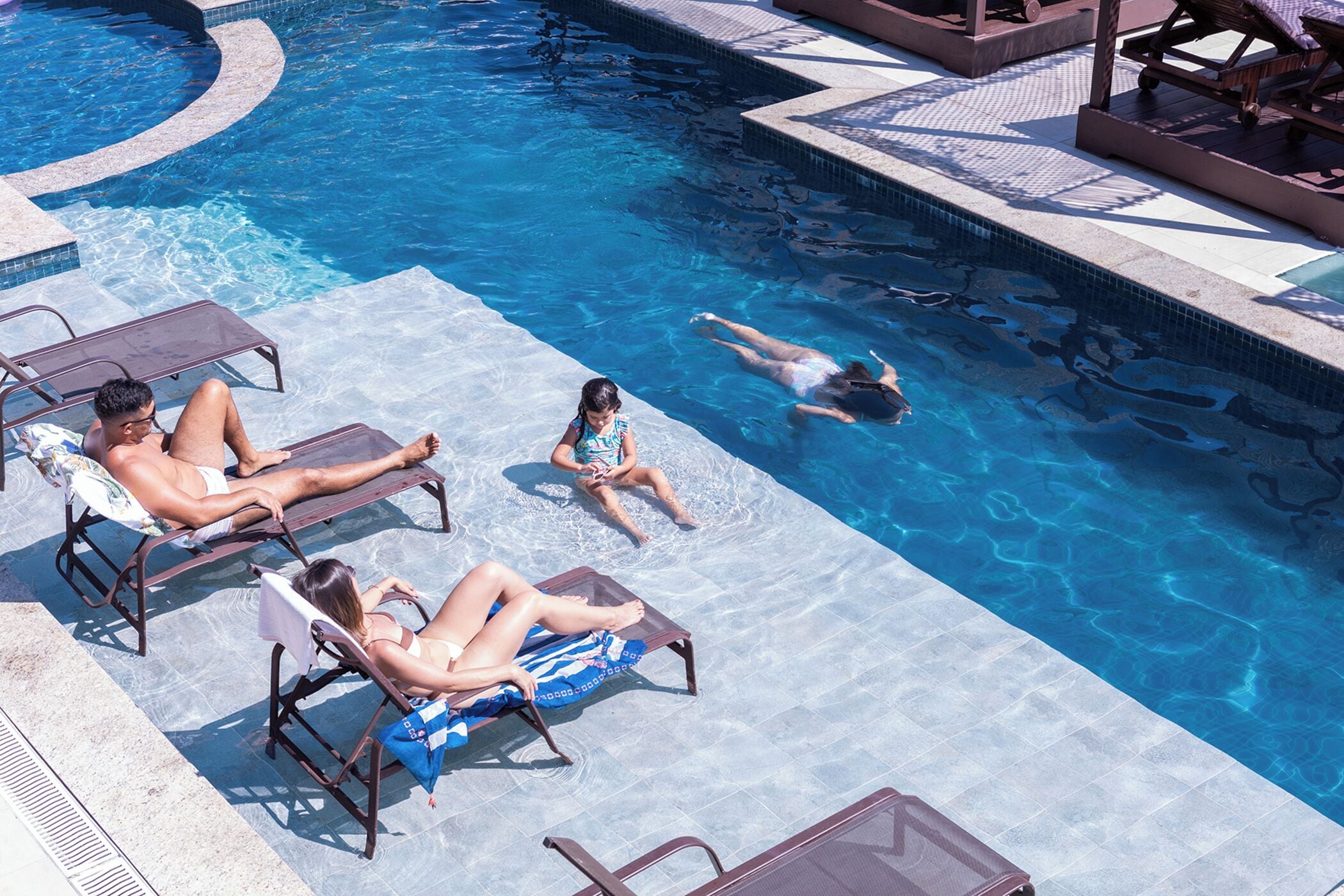 A swimming pool with lounge chairs and a sunbed.