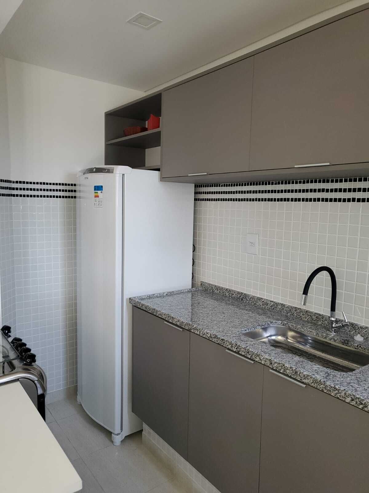 A kitchen with a white refrigerator, a granite countertop, a stainless steel sink, and a black faucet.