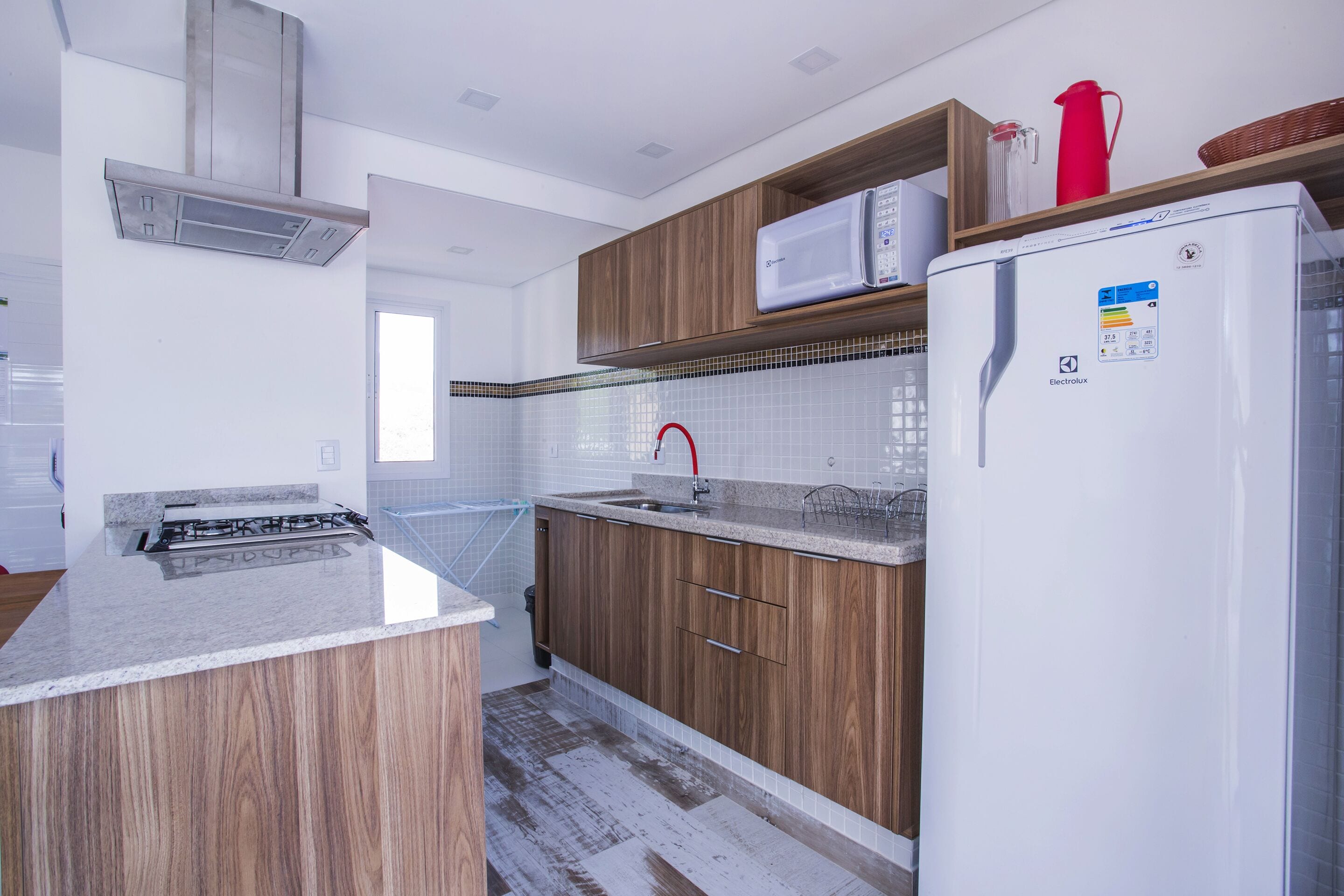 Una cocina moderna con armarios de madera, microondas integrado y campana extractora de acero inoxidable.