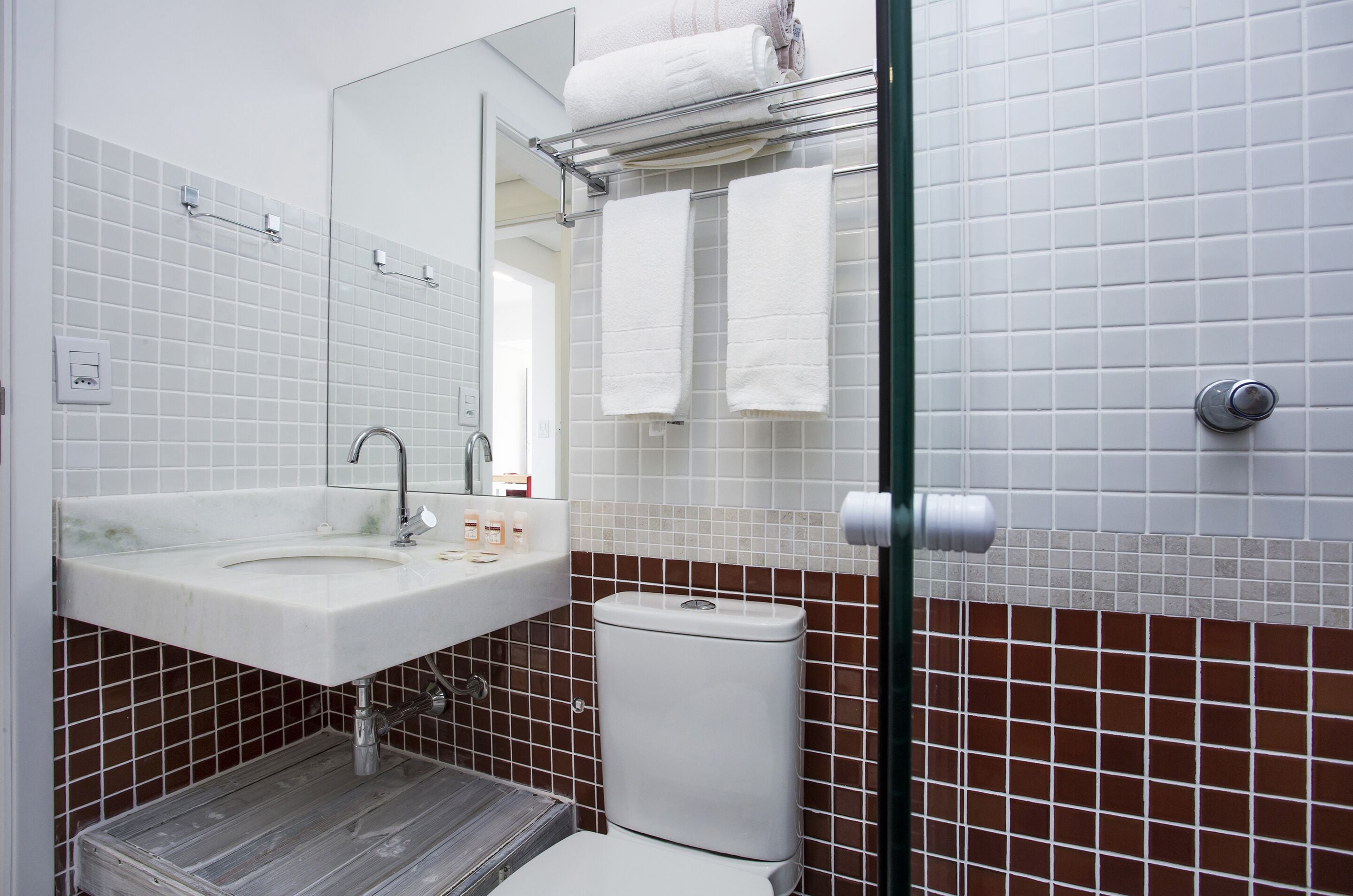 A bathroom with a white sink, a mirror, a toilet, and a shower area.