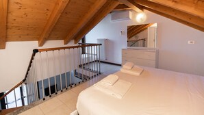 Ein Schlafzimmer mit Holzboden, einem Bett mit weißer Bettwäsche, einem Nachttisch und einem Spiegel.